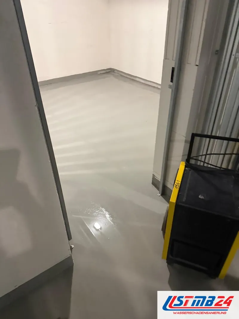 Bautrocknung in Grömitz: Kellerraum im Neubau, Wasser glänzt auf dem grauen Boden, im Gang ein schwarz-gelber Bautrockner