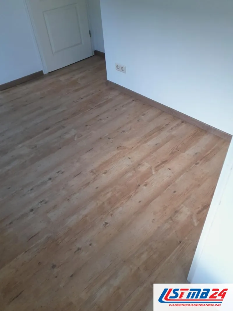 Bodenleger in Grömitz: neuer Laminatboden in Holzoptik im leeren Zimmer, Kassettentür und Doppelsteckdose