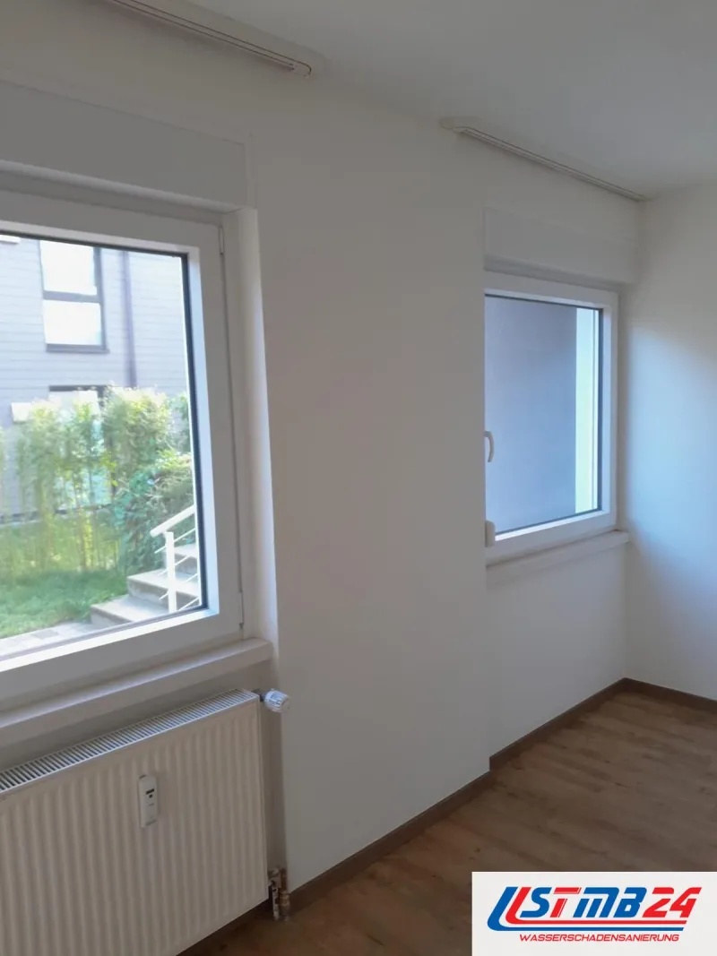 Bodenleger in Grömitz: renoviertes Zimmer mit Holzboden, Heizkörper unter dem Fenster, draußen Garten und Außentreppe