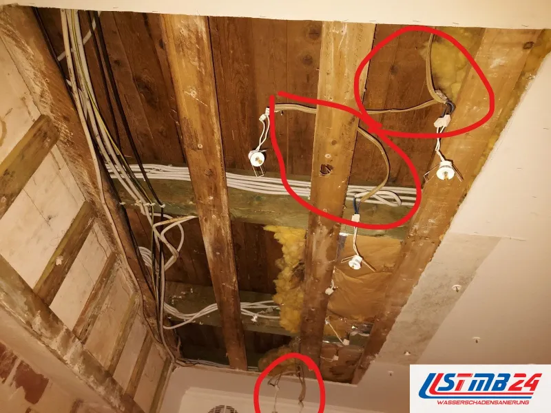 Elektriker in Grömitz: geöffnete Holzbalkendecke, Kabel und Leuchtenfassungen hängen frei, rote Kreise an Leitungen und Abzweigen