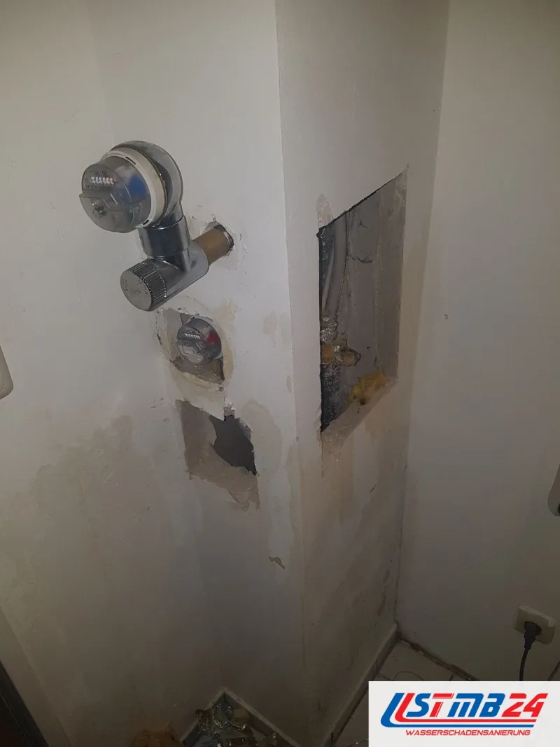 Fliesenleger in Grömitz: Wand mit Unterputz-Wasserzähler, zwei geöffneten Stellen und einer Steckdose, darunter Fliesenboden