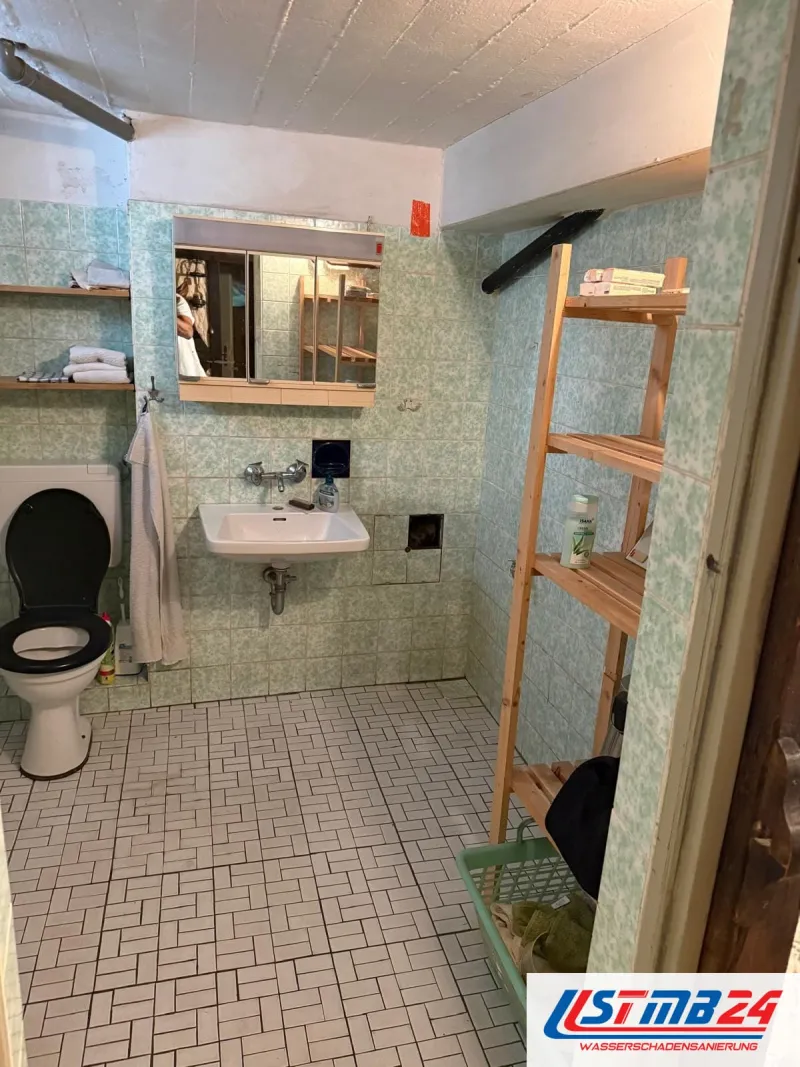 Fliesenleger in Grömitz: altes Bad mit grün gemusterten Wandfliesen, weißem Fischgrätboden, WC und Waschbecken