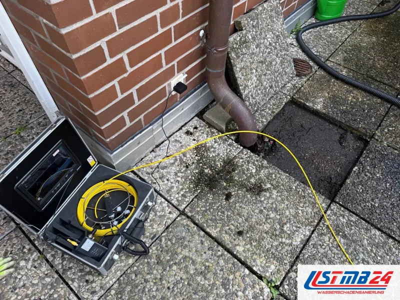 Leckortung in Grömitz: Rohrkamera im Koffer mit Monitor auf der Terrasse, das gelbe Kabel führt ins Regenfallrohr am Klinkerhaus