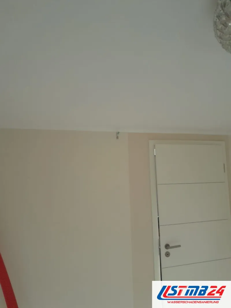 Maler in Grömitz: frisch gestrichene Wand neben einer weißen Zimmertür mit Querrillen, an der Decke eine Kristallleuchte