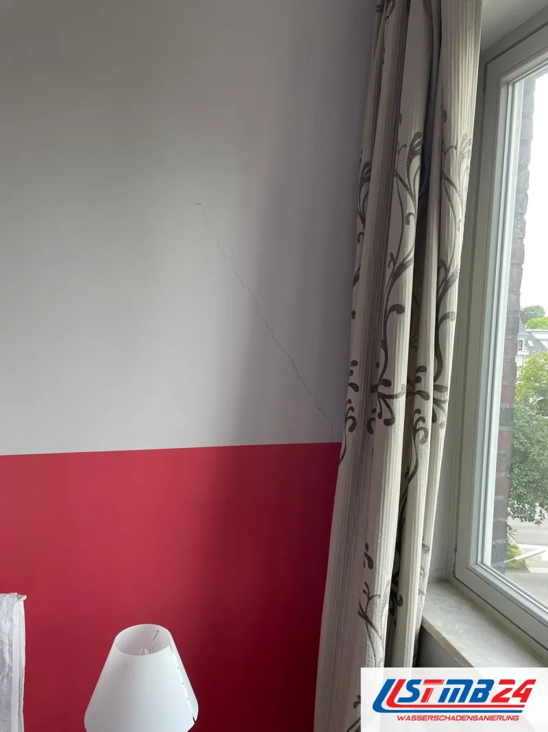 Maler in Grömitz: Wand mit rotem Sockelanstrich am Fenster, darüber ein feiner Riss im weißen Putz