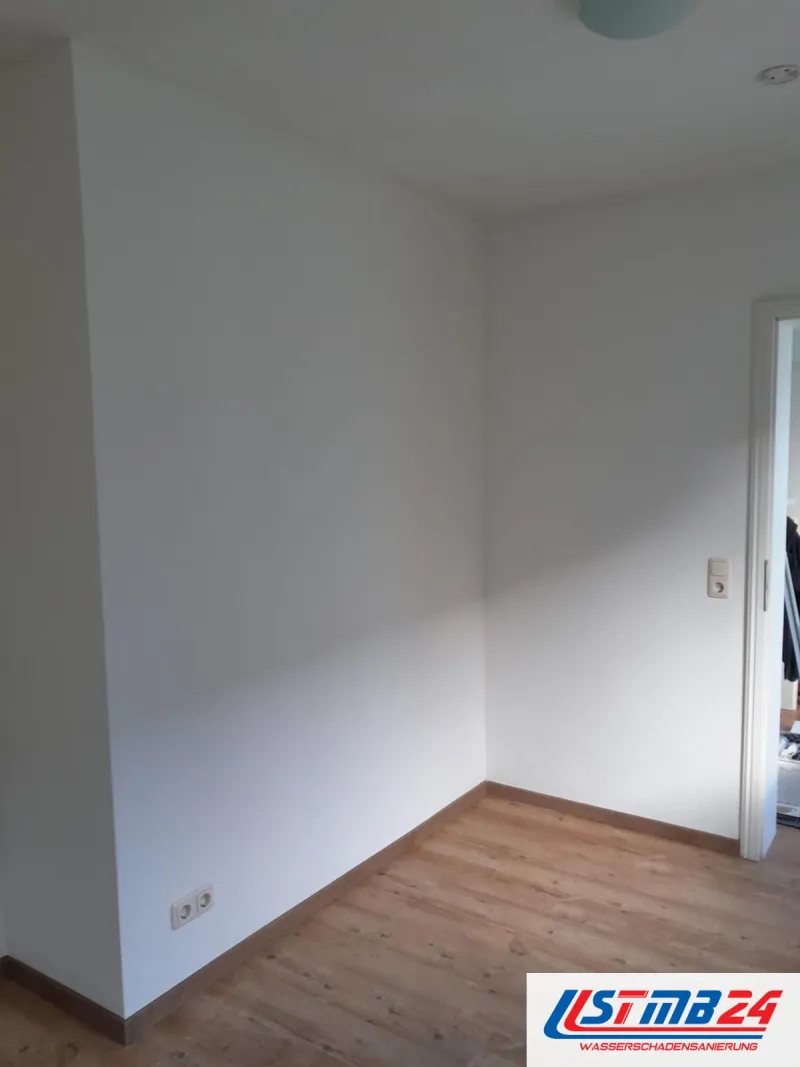 Maler in Grömitz: weiß gestrichenes Zimmer unter der Dachschräge, Holzboden mit Sockelleisten, die Tür steht offen