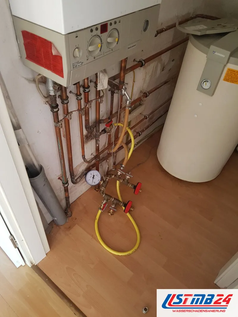 Sanitär und Heizung in Grömitz: Gastherme an der Wand, Kupferleitungen mit Manometer und gelbem Schlauch, daneben der Speicher