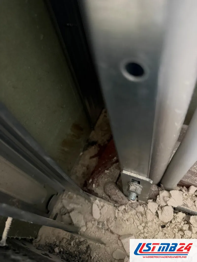 Trockenbau in Grömitz: Metallständer am Boden mit Winkel und Schraube befestigt, ringsum Gipsreste