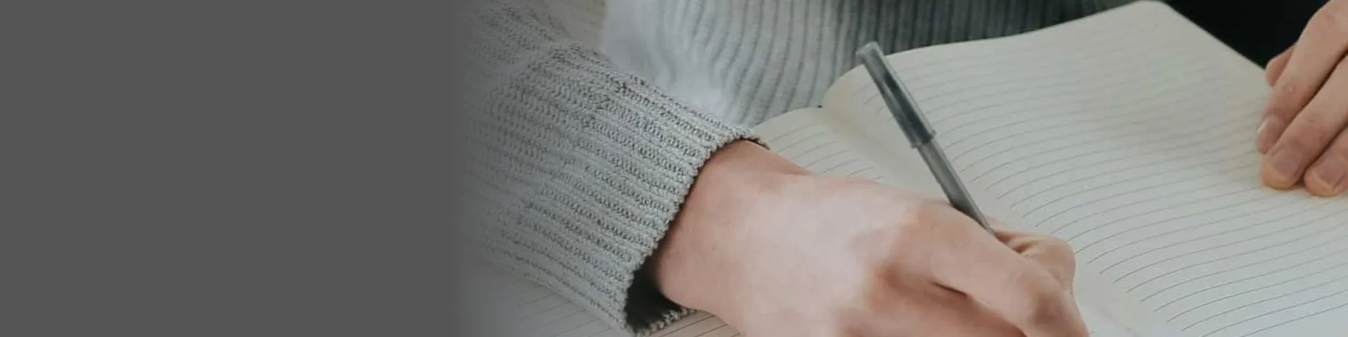 Fachbegriffe von A bis Z: Hand mit Stift schreibt in ein aufgeschlagenes Notizbuch