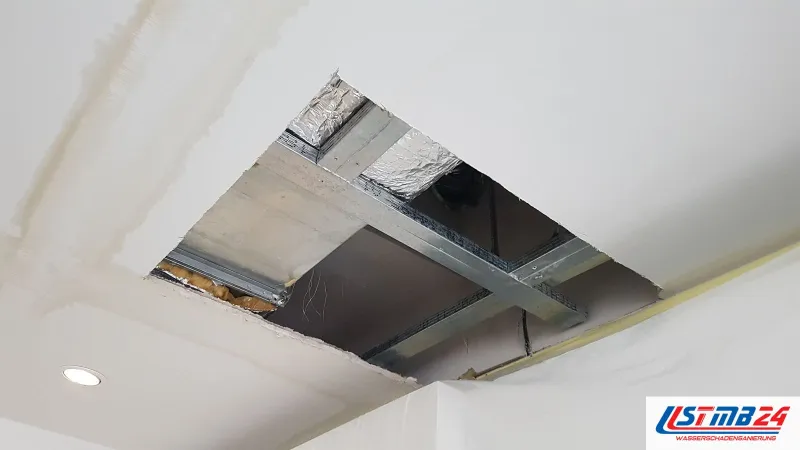 Trockenbauarbeiten an der Decke: ausgeschnittene Öffnung in der Gipskartondecke, darüber Metallprofile, Alu-Dämmung und eine Leitung