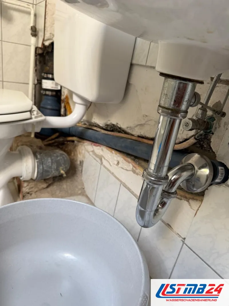 Ursachen von Wasserschäden: Wand unter dem Waschbecken aufgestemmt, Abflussrohre und Wasserleitungen liegen frei