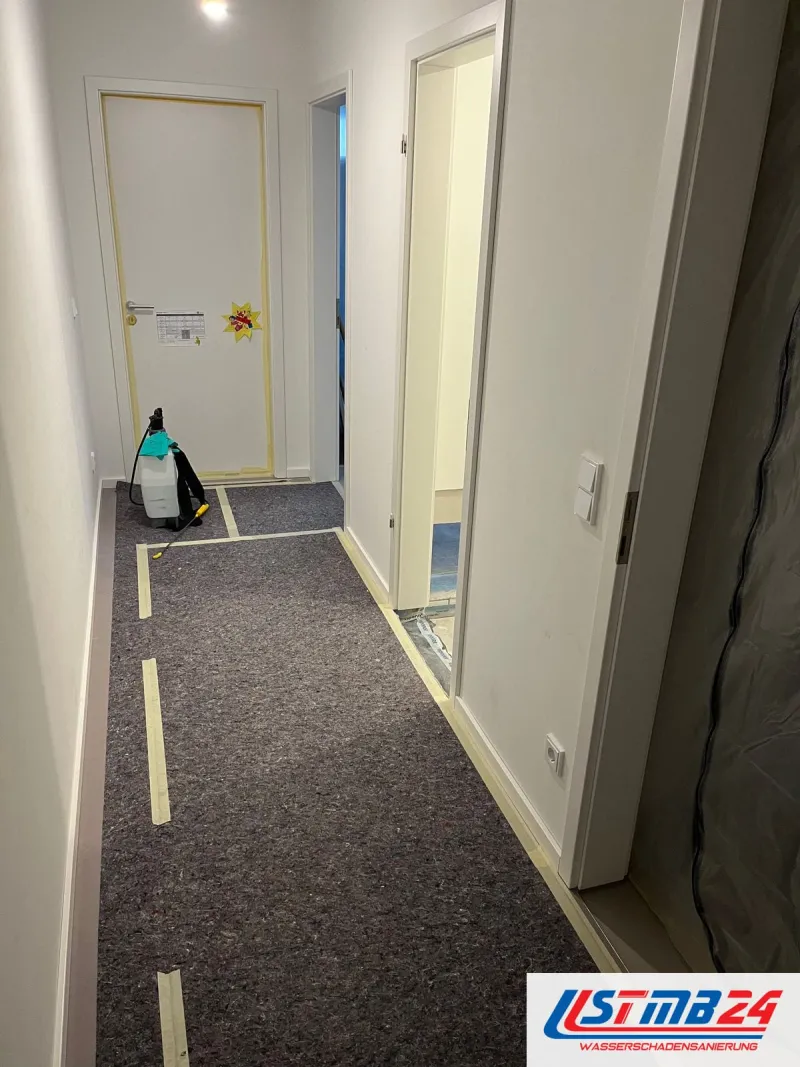 Flur einer Wohnung bei der Wasserschadensanierung, Boden mit Abdeckvlies geschützt, Türrahmen abgeklebt