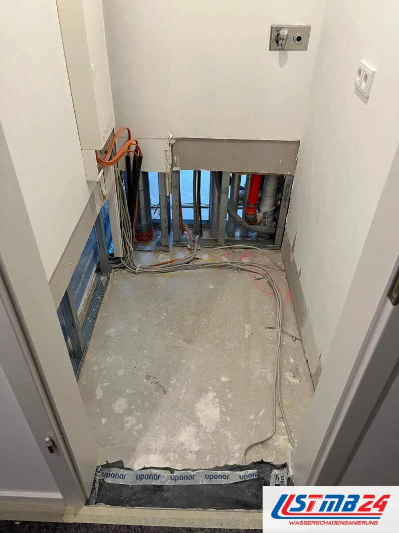 Bad mit zurückgebautem Boden, die Vorwand unten geöffnet, dahinter freigelegte Rohrleitungen
