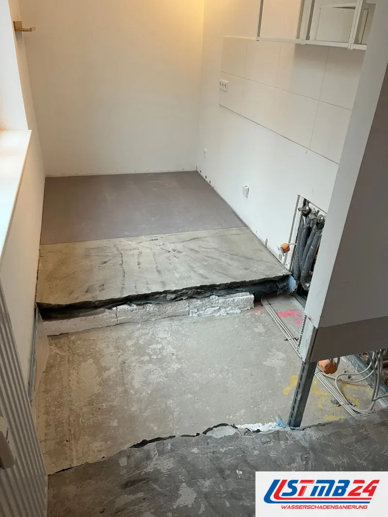 Aufgetrennter Estrich in einer Küche, darunter die Dämmschicht, rechts eine geöffnete Vorwand mit Leitungen